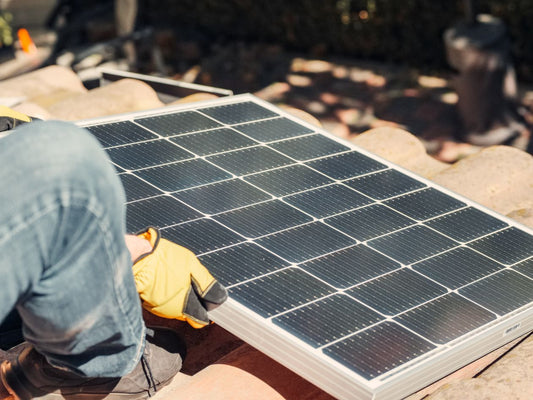 Worker installing a solar panel on a rooftop